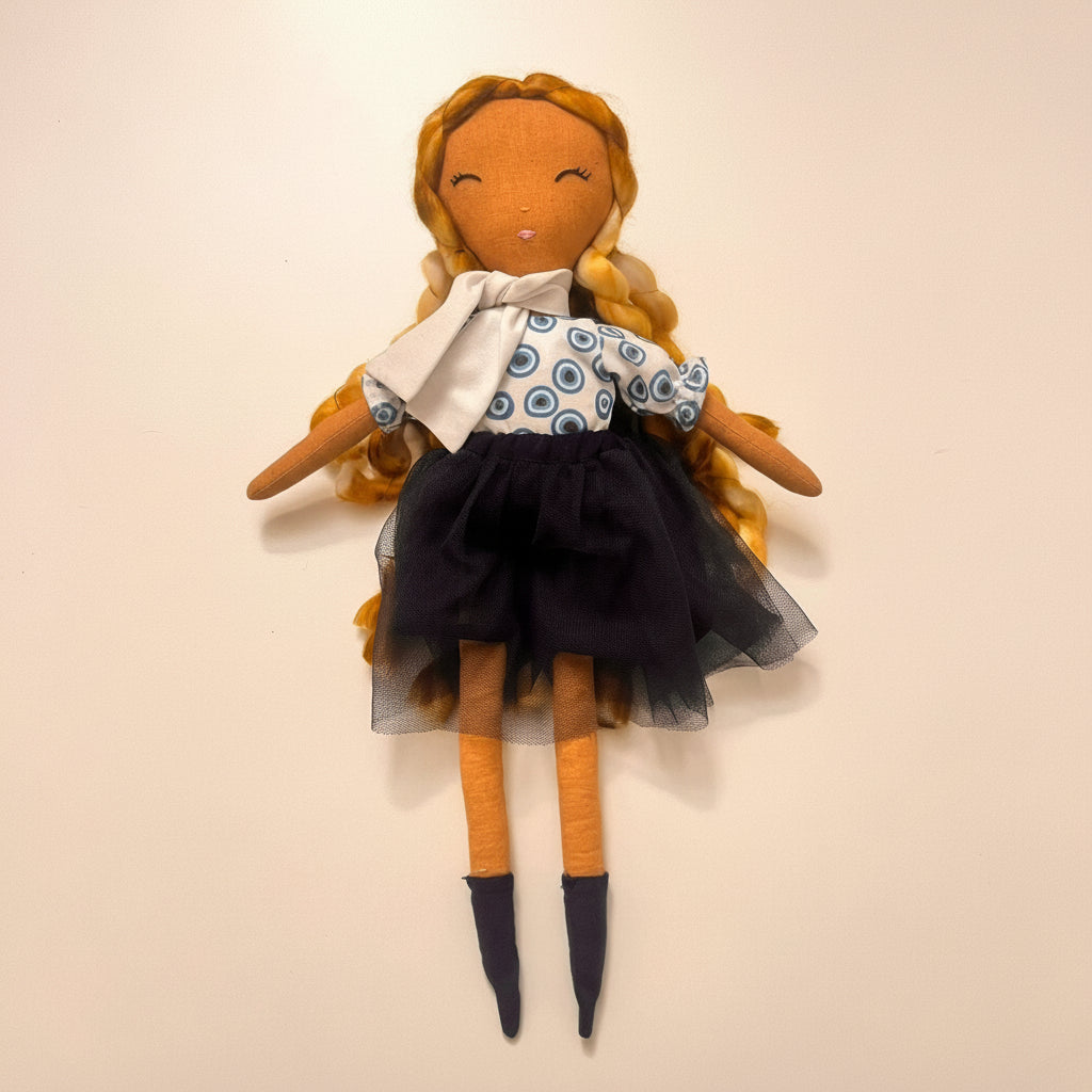 Handmade doll with blonde hair, blue eyes, and a black dress on a beige background