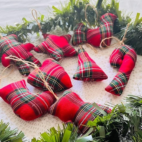 Red plaid Christmas ornaments on a white surface with greenery
